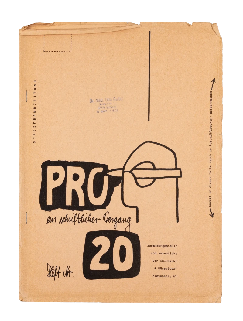 Dünne beige Pappe. Darauf ein von Hand geschriebener Titel und die Illustration einer Hand die einen Stift hält.